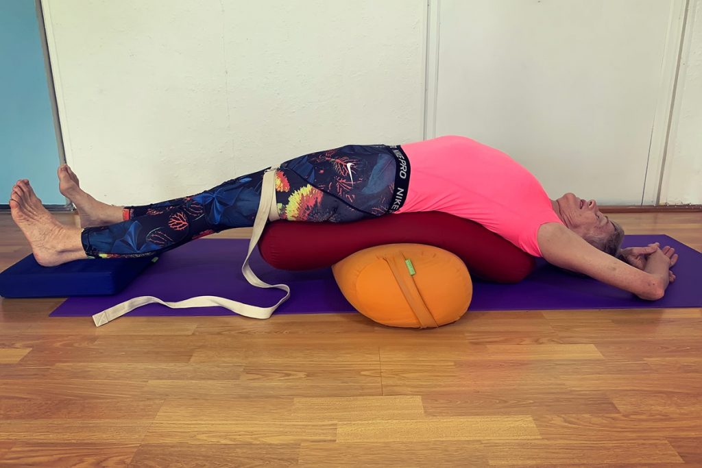 Chris lying back over a bolster with a strap