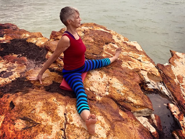 Mother and daughter exercising yoga on beach, low angle view stock photo