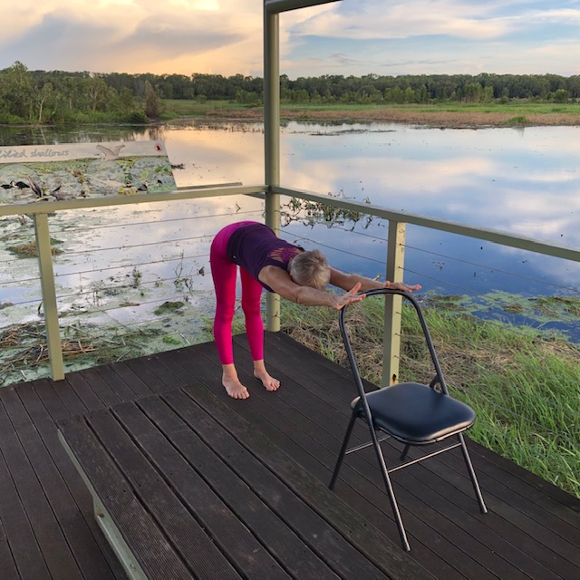 Yoga for neck pain: Half Dog Pose with the hands on a railing, lengthening the spine and freeing the shoulders