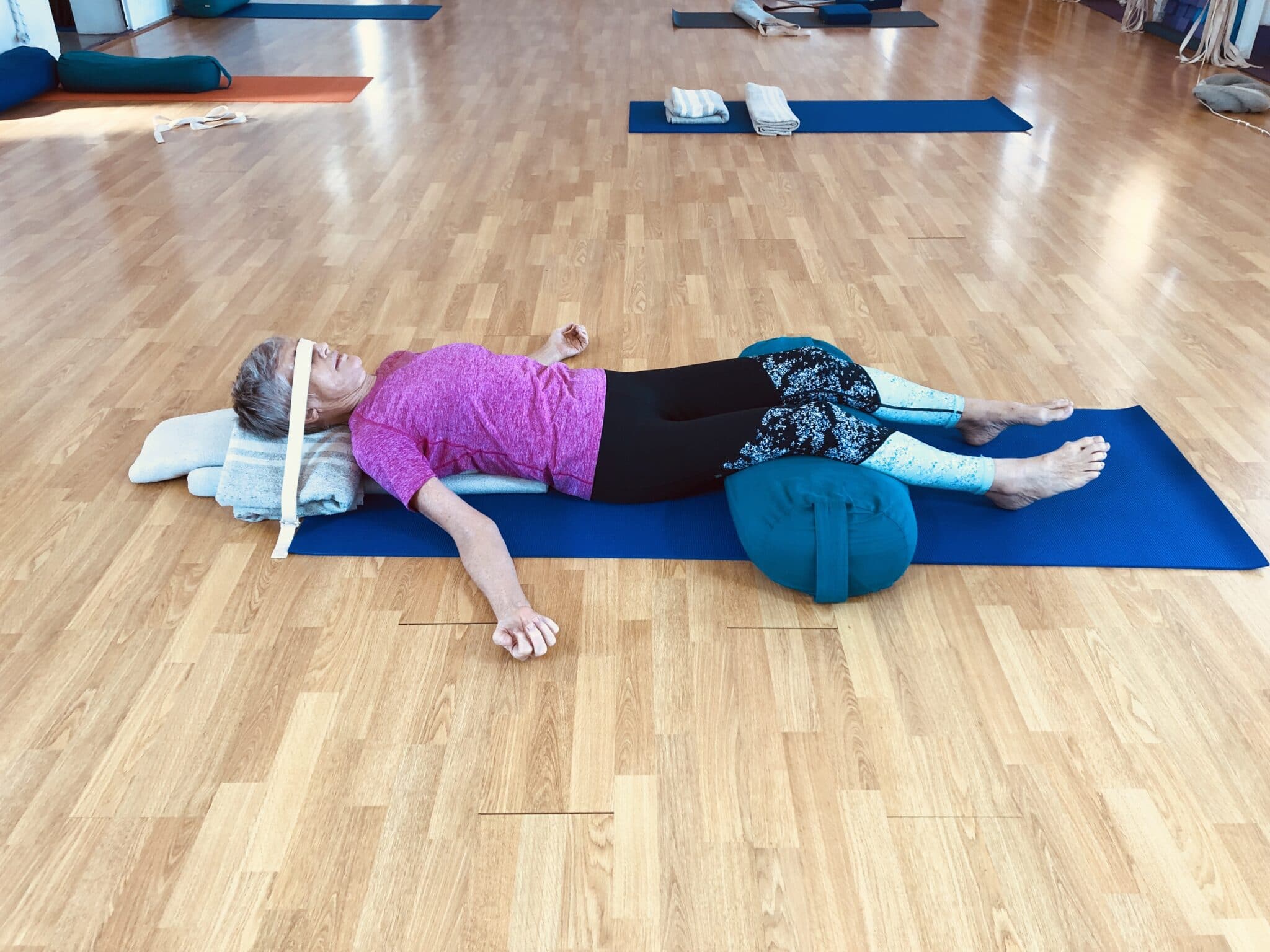Lying on a mat with a bolster under the knees, a calm position for slow breathing before sleep