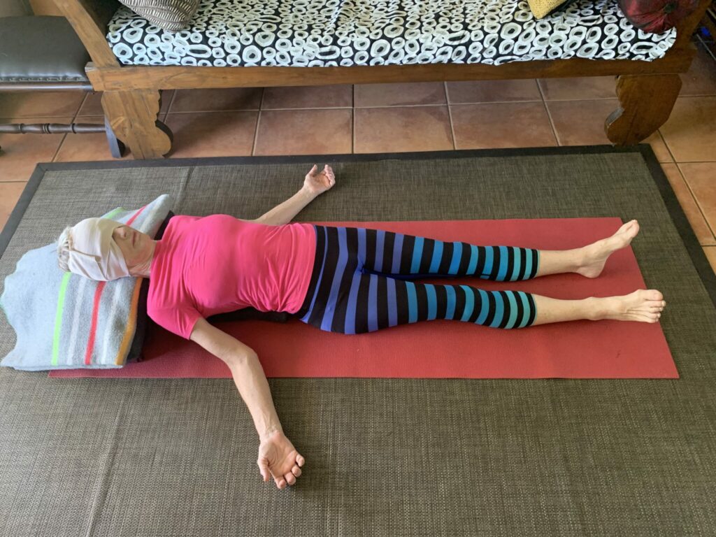 A woman resting in relaxation pose with an eye bag