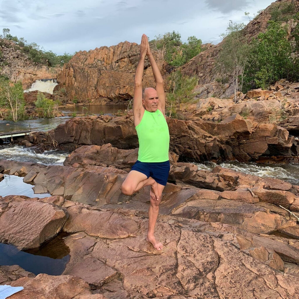 Stuart McGill in Tree Pose with arms raised at Edith Falls