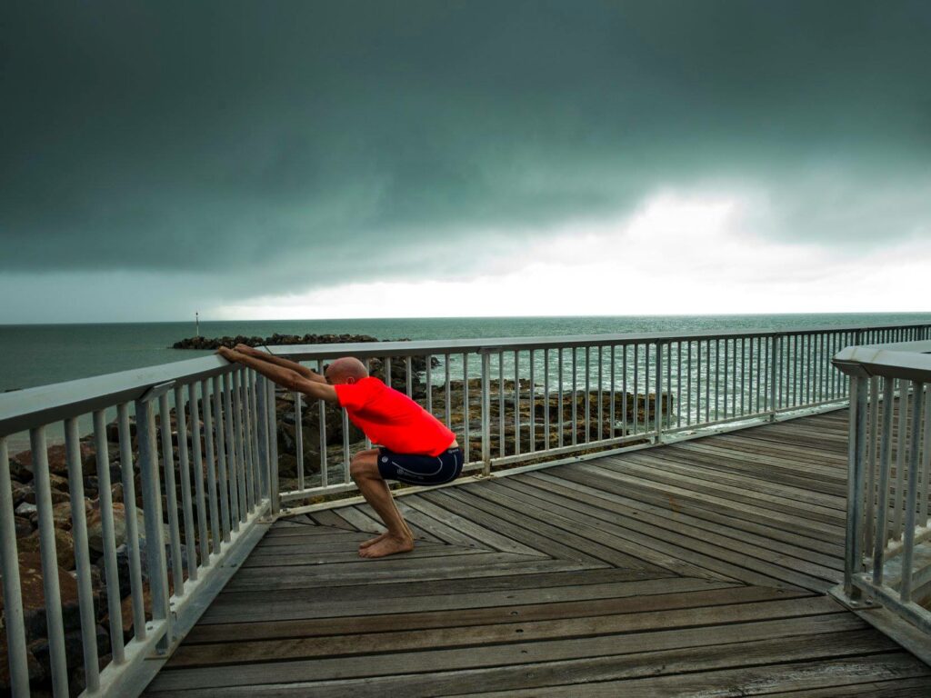 Stuart from Flametree's health & yoga hub Darwin demonstrating malasana yoga pose preparation at Nightcliff NT