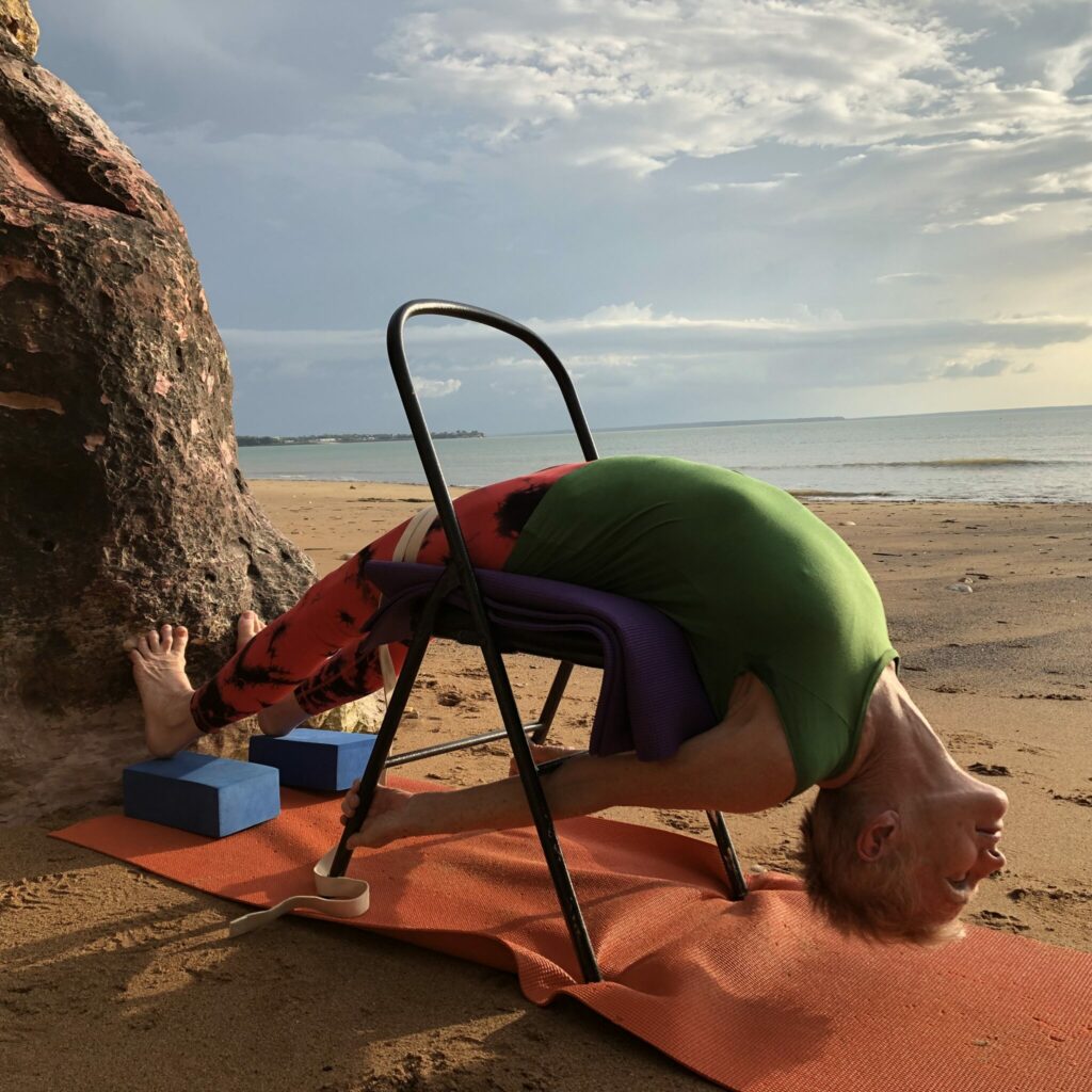 Yoga for kyphosis: supported backbend over a chair on a Darwin beach