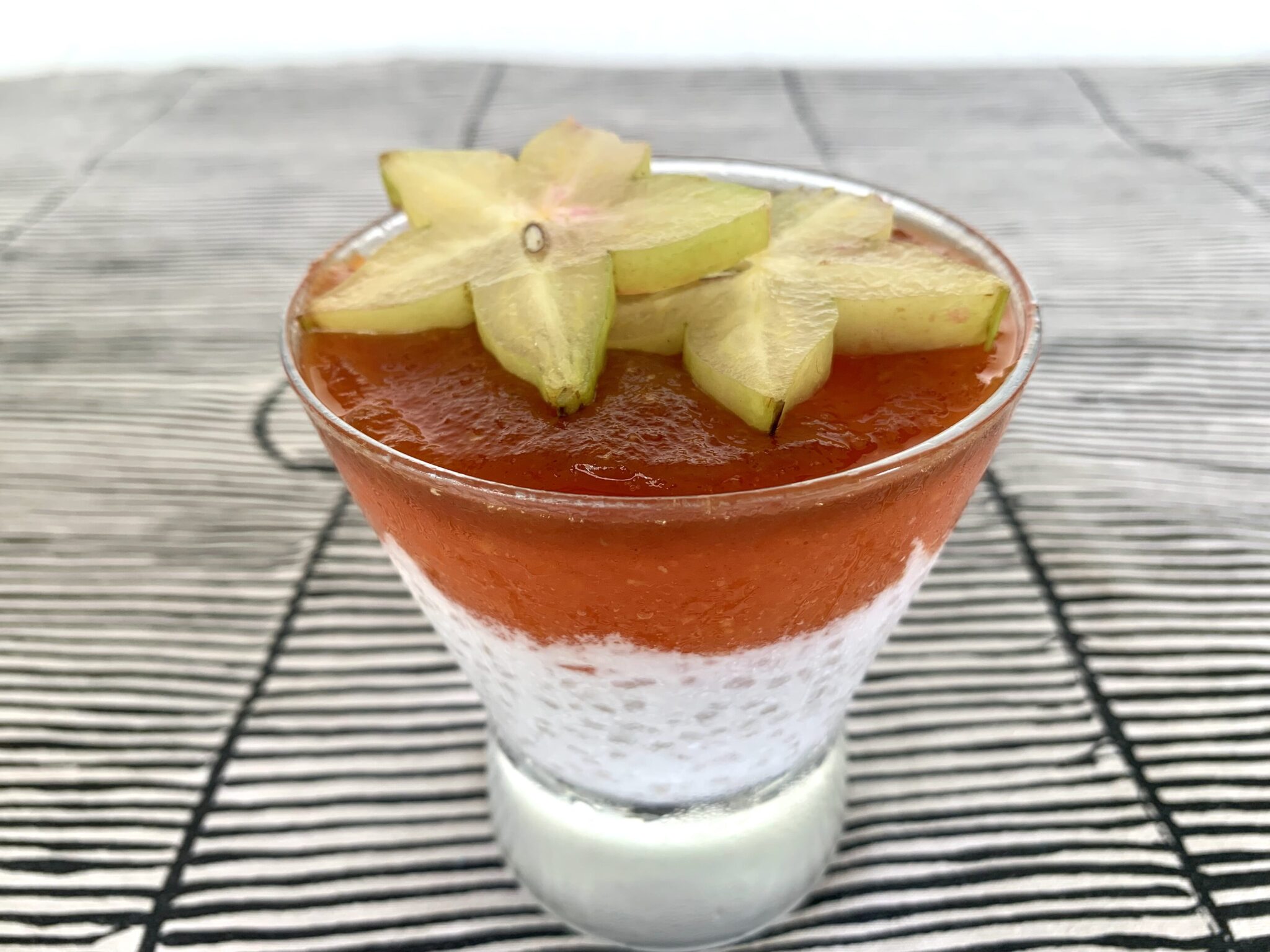 Tapioca pearl dessert in a glass with papaya puree on top and star fruit