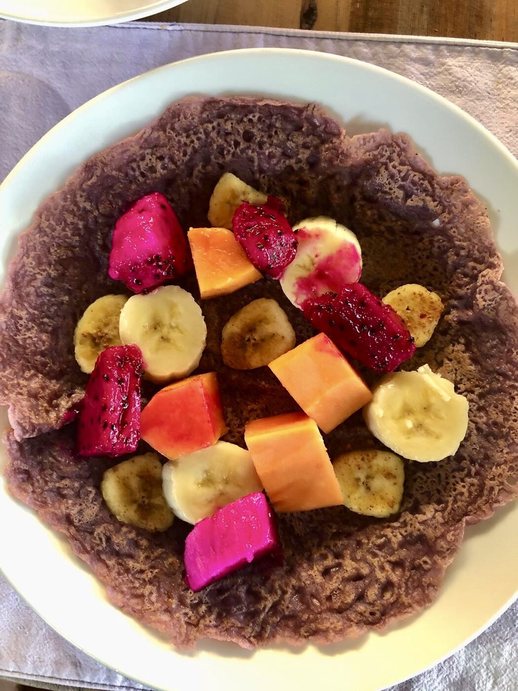 Black rice pancakes with fresh tropical fruit, served at Pondok Pisang on the Flametree Bali retreat