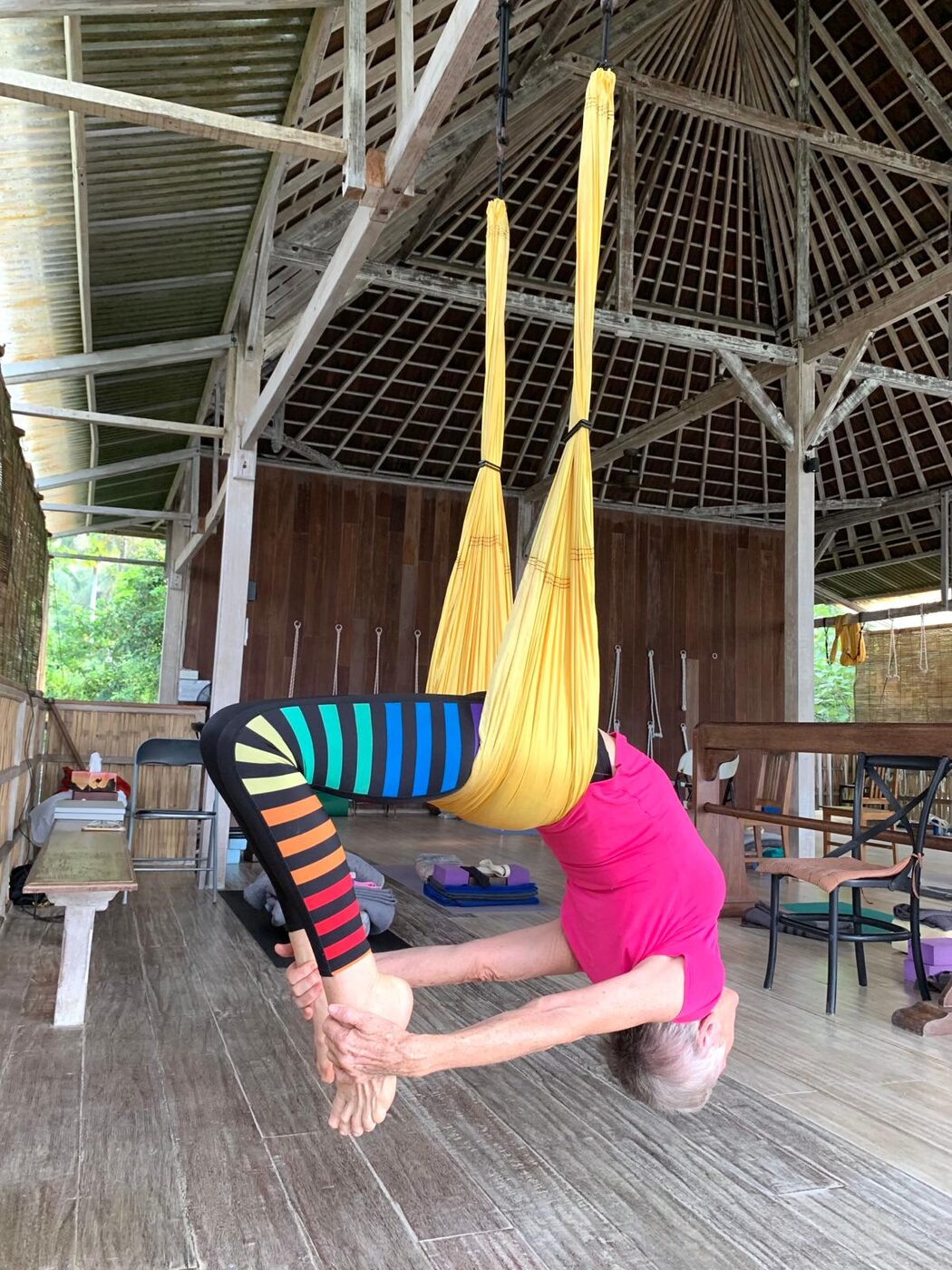 A supported backbend in the yoga swing at the Flametree Bali retreat