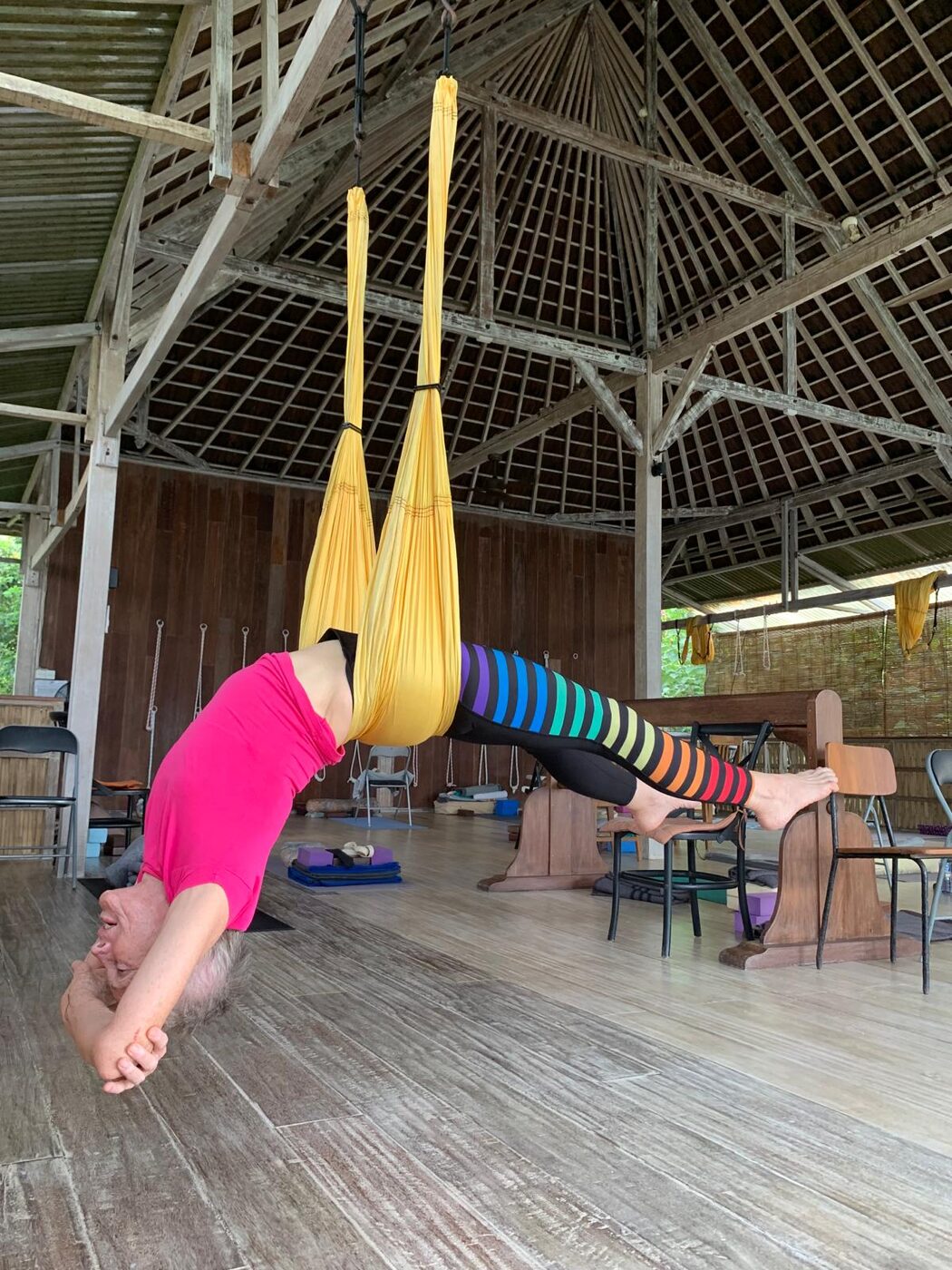 Hanging forward bend in the yoga swing at the Flametree Bali retreat