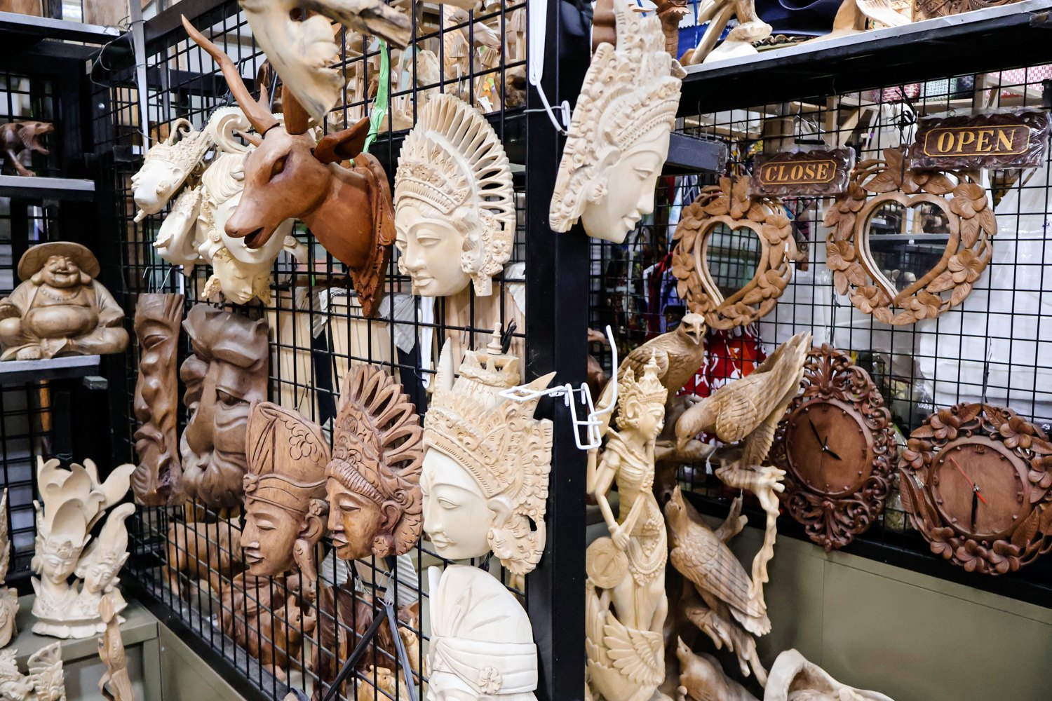 Hand carved wooden masks, figures and mirror frames hanging on a stall at Sukawati art market in Bali