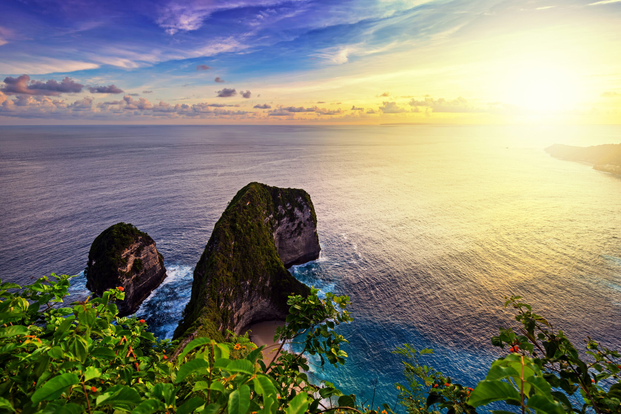 Sea stacks and high green cliffs above clear water on the coast of Nusa Penida, Bali