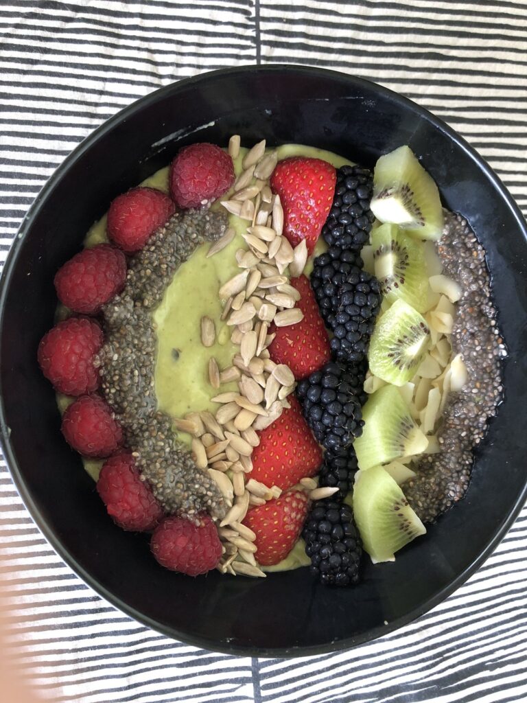 Avocado banana smoothie served as a bowl with chia, berries, kiwi and seeds