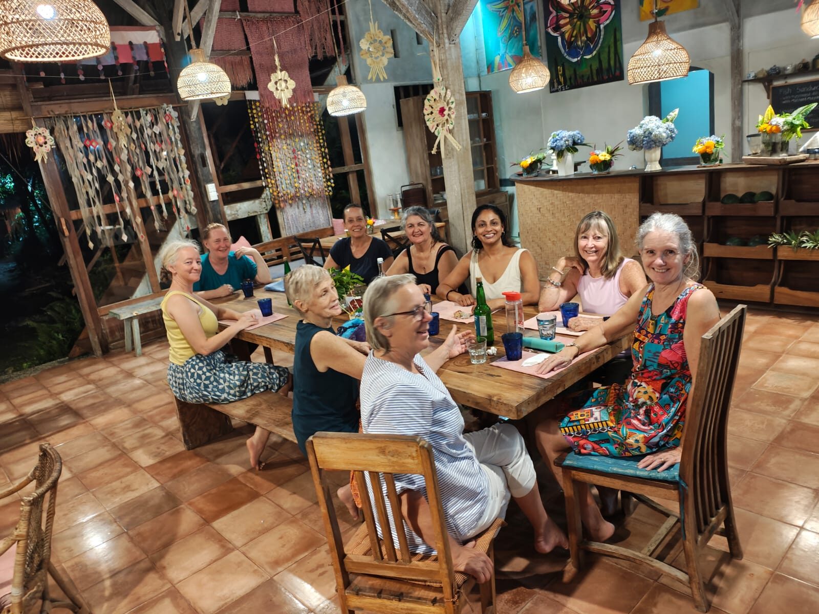 Flametree retreat guests eating dinner together at the long table in the dining room at Pondok Pisang, Bali