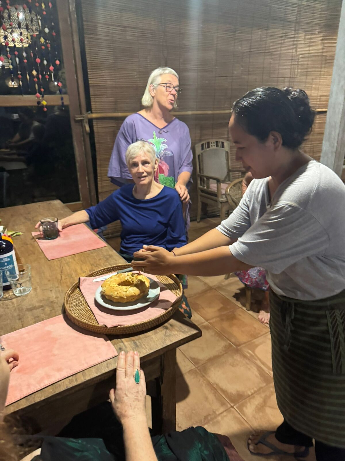 Kitchen staff carrying out a cake to the dinner table at Pondok Pisang during a Flametree Bali retreat