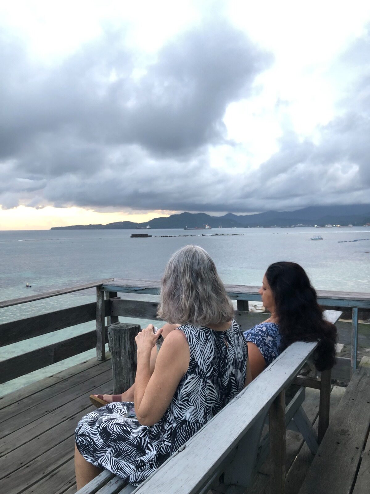 Two women sitting on a bench looking out at the sea at a Bali yoga retreat in Candidasa