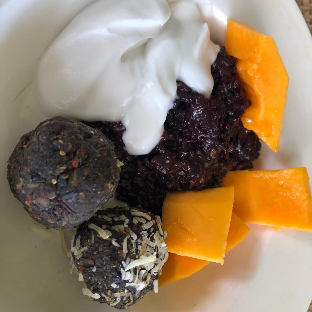 Healthy bliss balls served as a dessert with black rice pudding, coconut yoghurt and Darwin paw paw