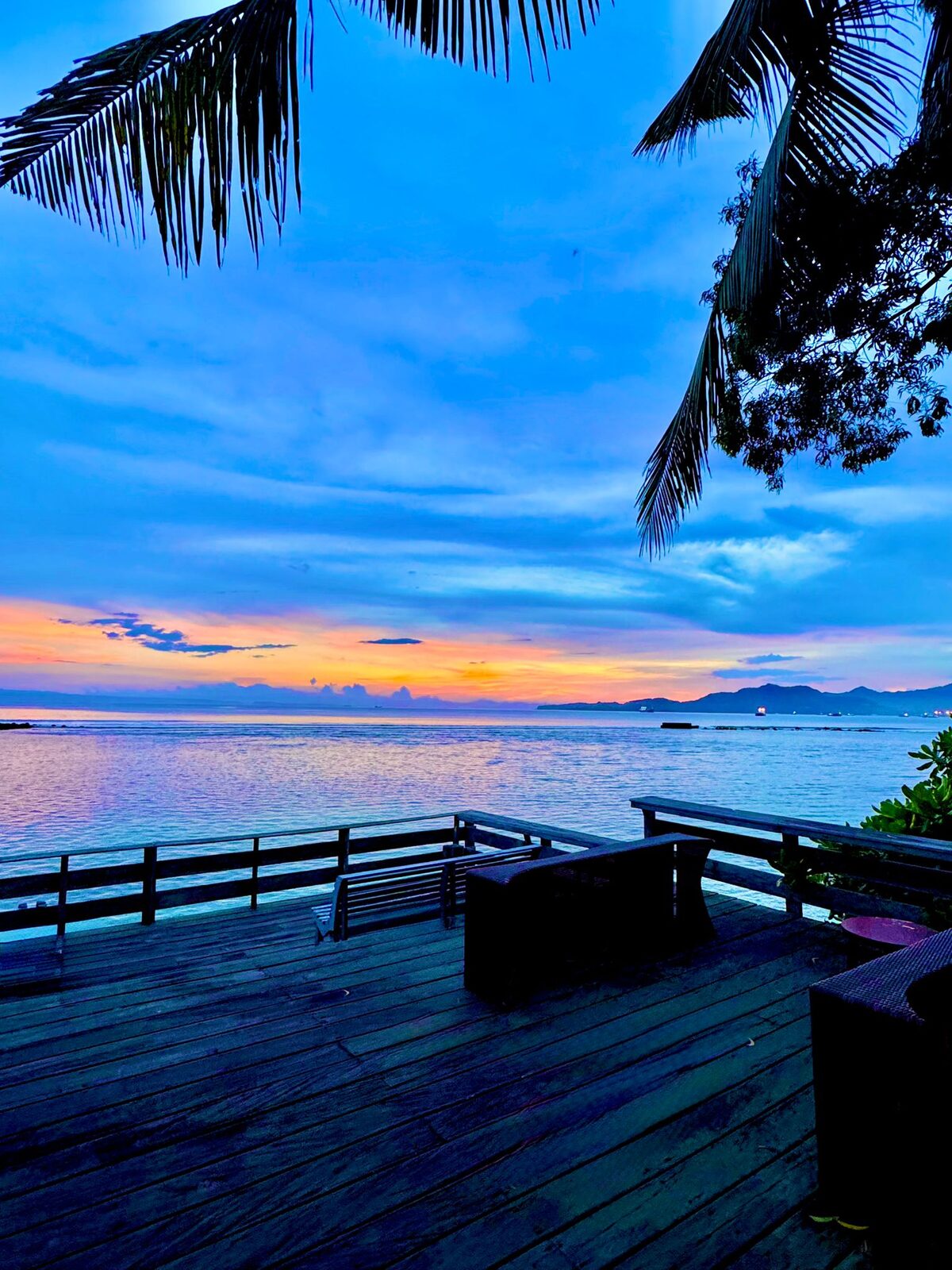 Sunset seen through palm trees over the water at Candidasa, Bali