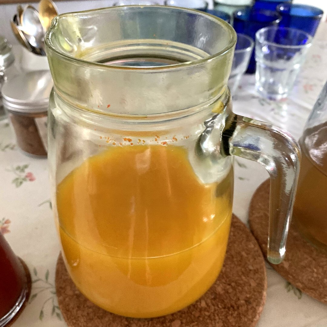 Yoga retreat experience: a glass jug of orange turmeric drink on a cork mat on the lunch table at a Flametree Bali retreat