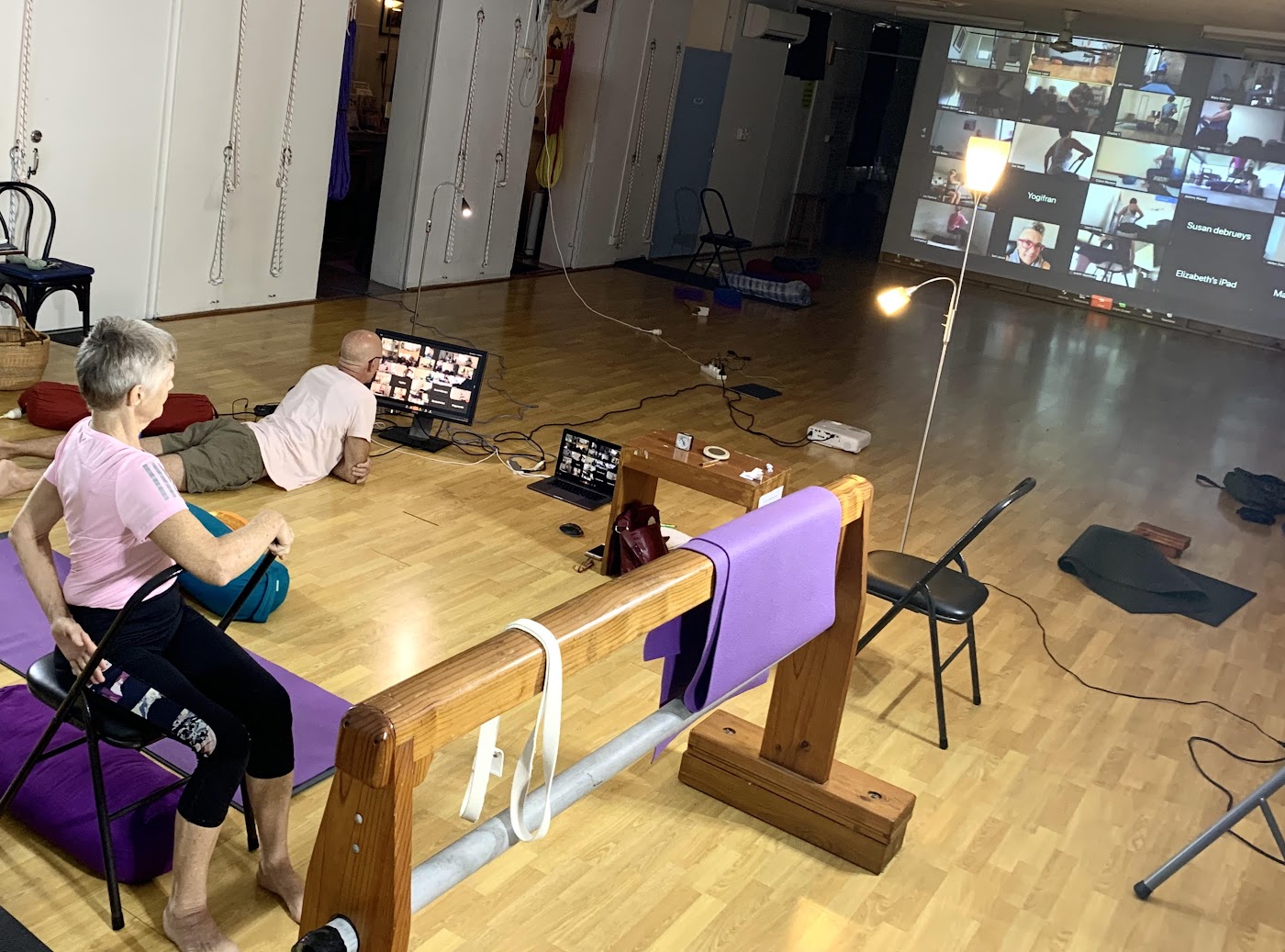 Beginner yoga classes Darwin: teachers watching online students on the studio wall