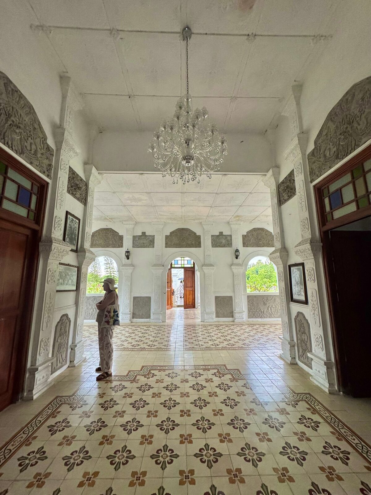 Inside the Bale Gili pavilion at Taman Ujung, with patterned tiled floors, arches and a chandelier