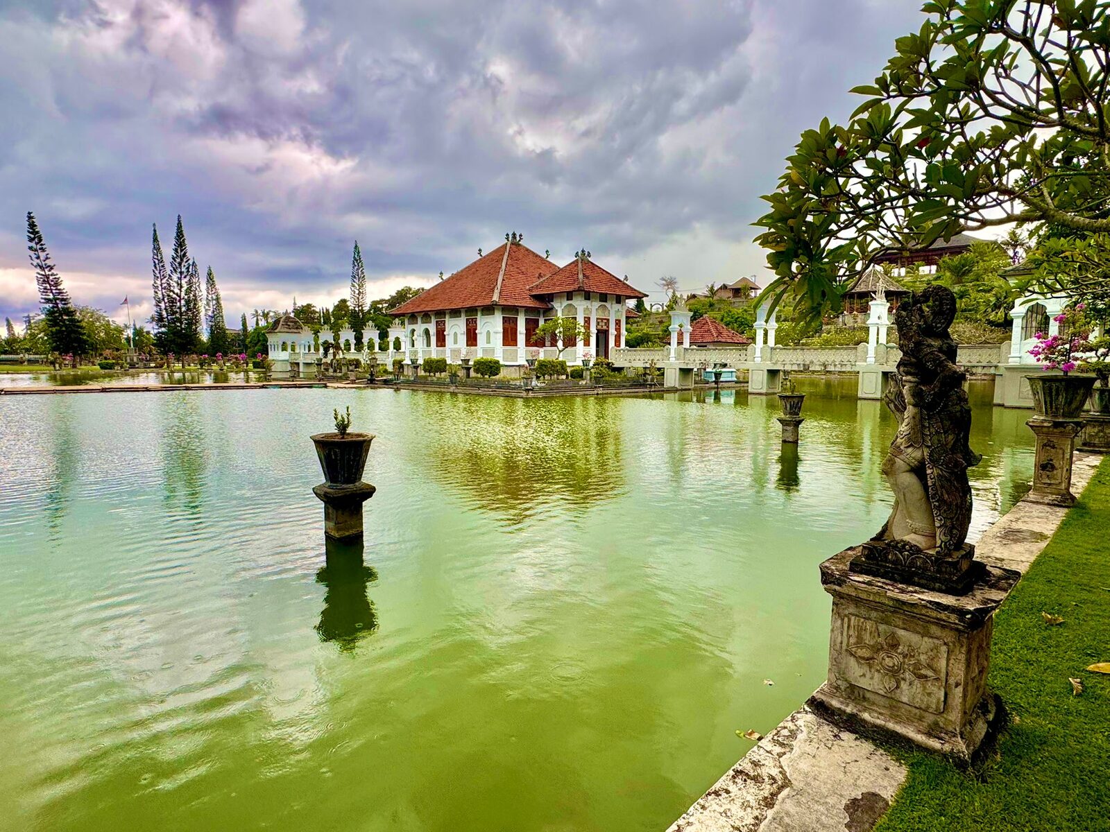 The pools and stone lanterns at Taman Ujung water palace with the palace buildings behind
