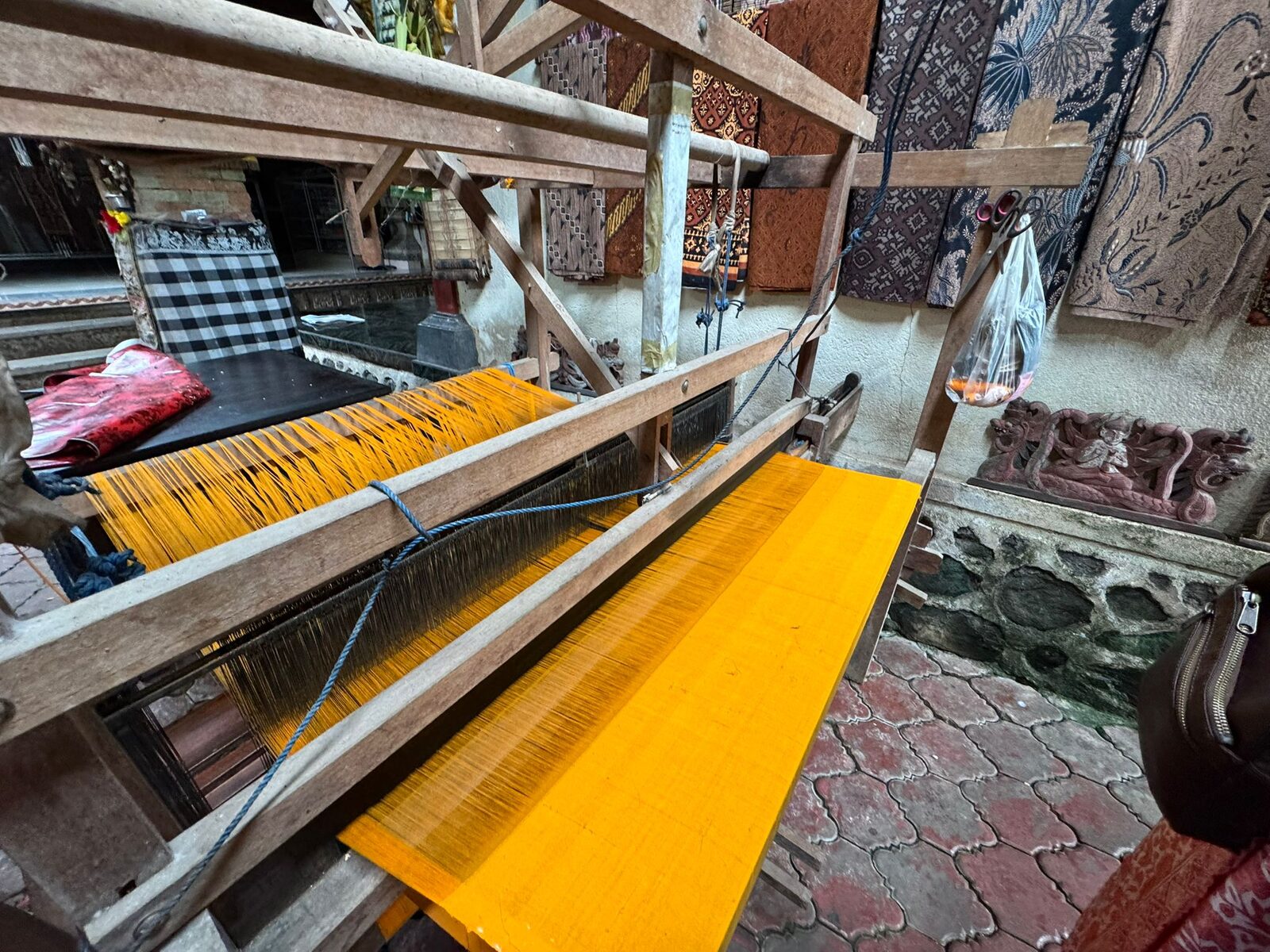 A backstrap loom in Tenganan with yellow warp threads stretched along it for geringsing double ikat weaving