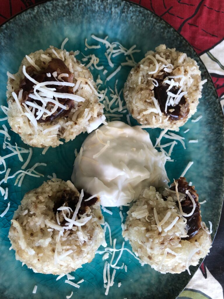 Steamed cassava balls with a date in the centre and grated coconut, served with yoghurt on a blue plate