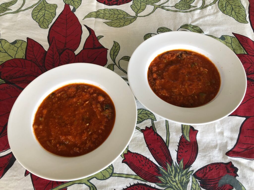 Two white bowls of fresh tomato soup made with leek, celery and green beans
