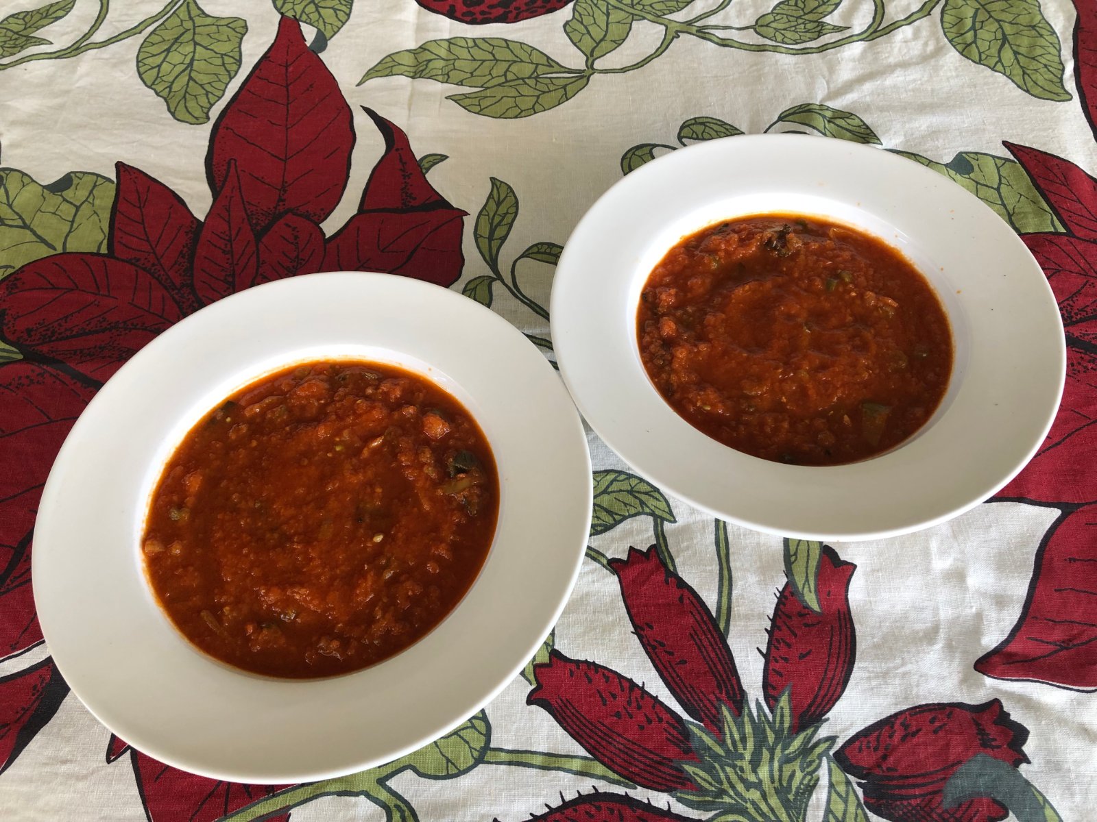 Two white bowls of fresh tomato soup made with leek, celery and green beans