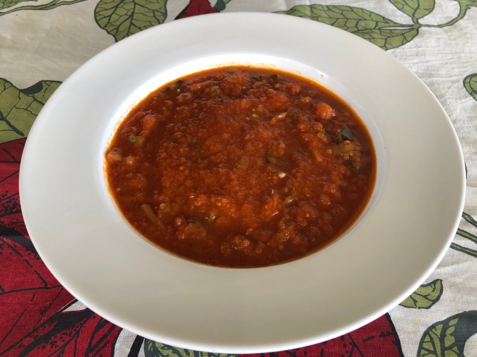 Homemade tomato soup with finely chopped green beans in a wide white bowl
