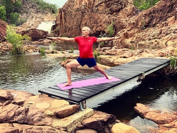 Hunched back and posture: Stuart McGill of Flametree in Warrior 2 on a boardwalk over rock pools, arms strong and level, chest lifted