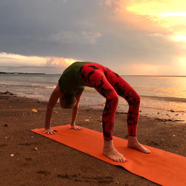 Iyengar yoga Wheel Pose (Urdhva Dhanurasana), a full backbend, on a Darwin beach at sunset