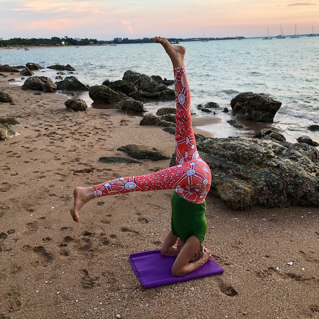 Iyengar yoga headstand variation (Sirsasana) with the legs split, on a Darwin beach at sunset