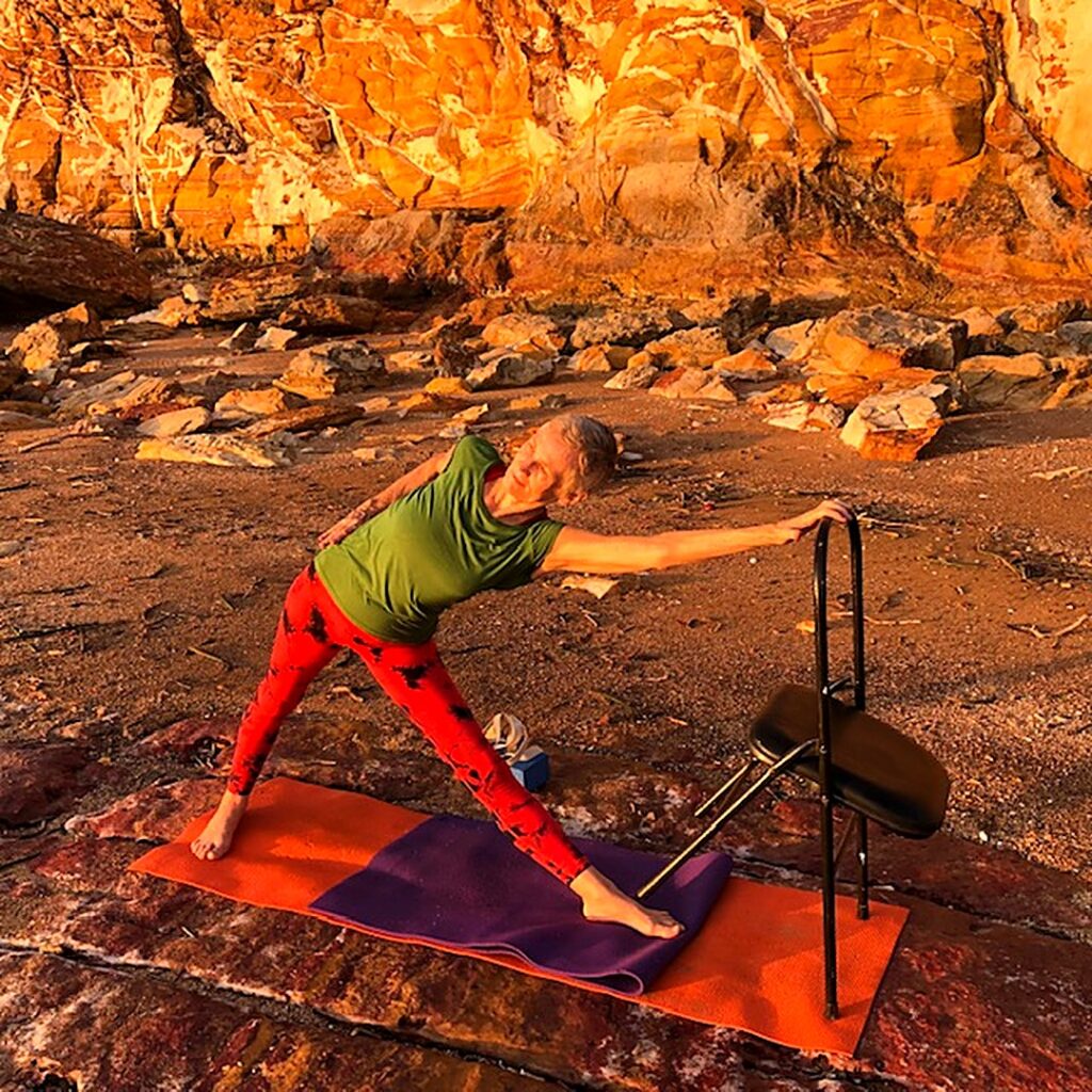 Neck pain from desk work: Chris Lalor in Triangle Pose with her hand on a chair, the upper back broad and working