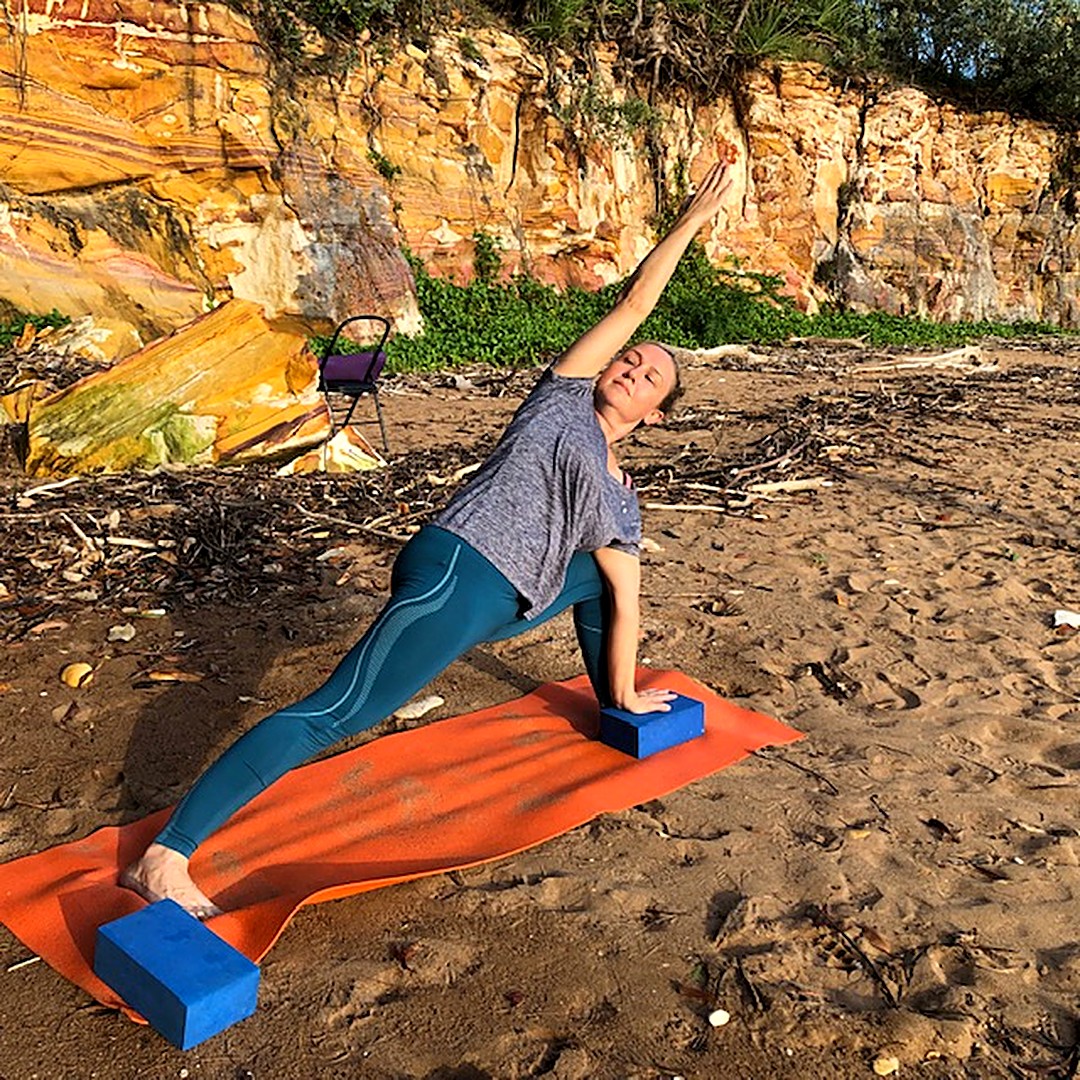 Yoga for light bladder leakage: Kim in Extended Side Angle Pose with a block on a Top End beach, building strength in the legs and pelvis