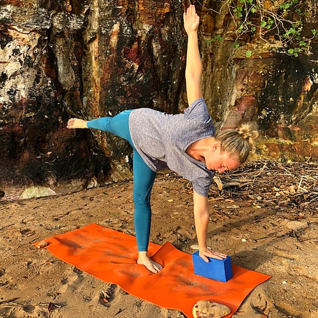 Upper back pain from sitting eases as the chest opens: Kim in Half Moon Pose with her lower hand on a block, arms in one line
