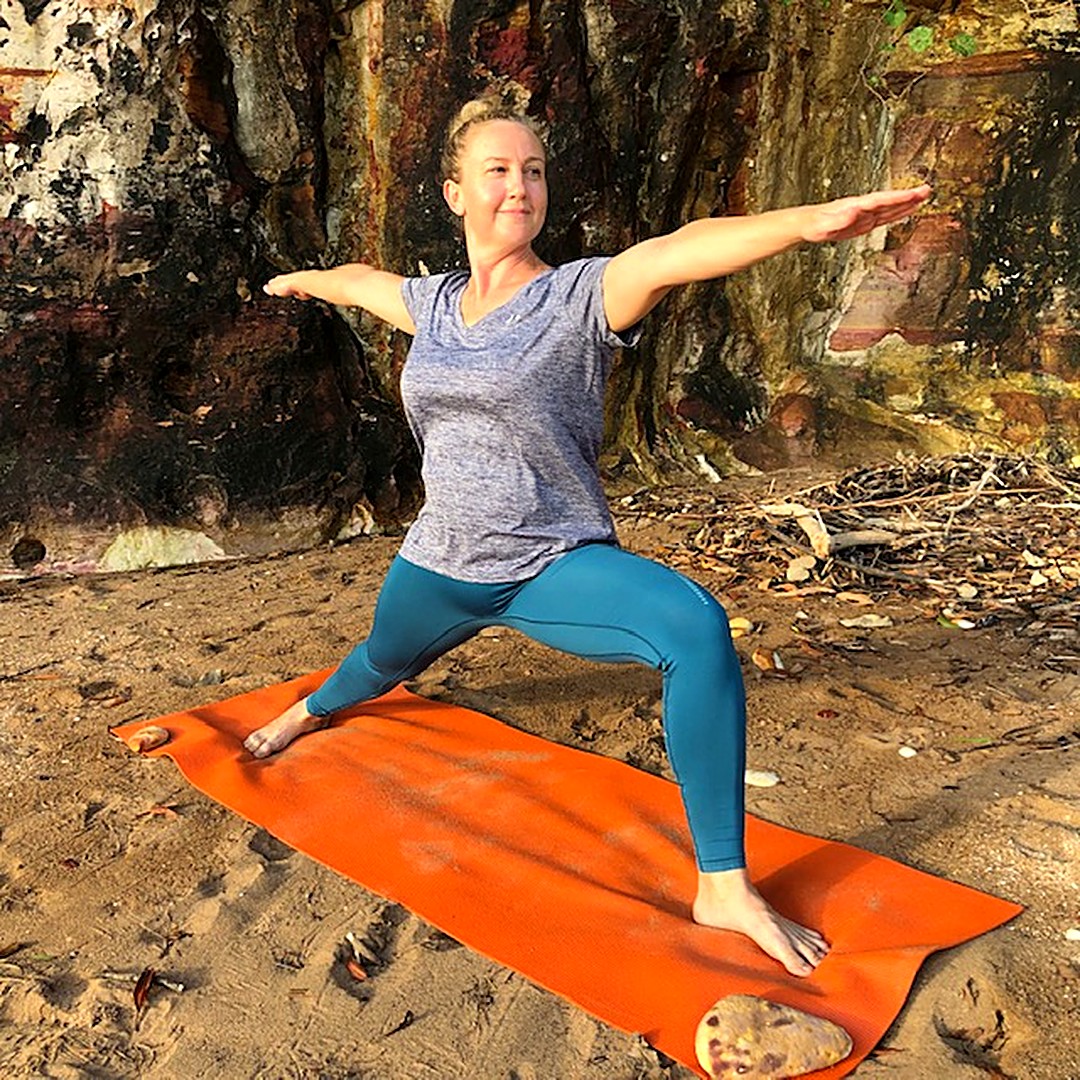 Yoga for balance: Kim in Warrior II on a beach, back leg straight and front knee bent over the ankle