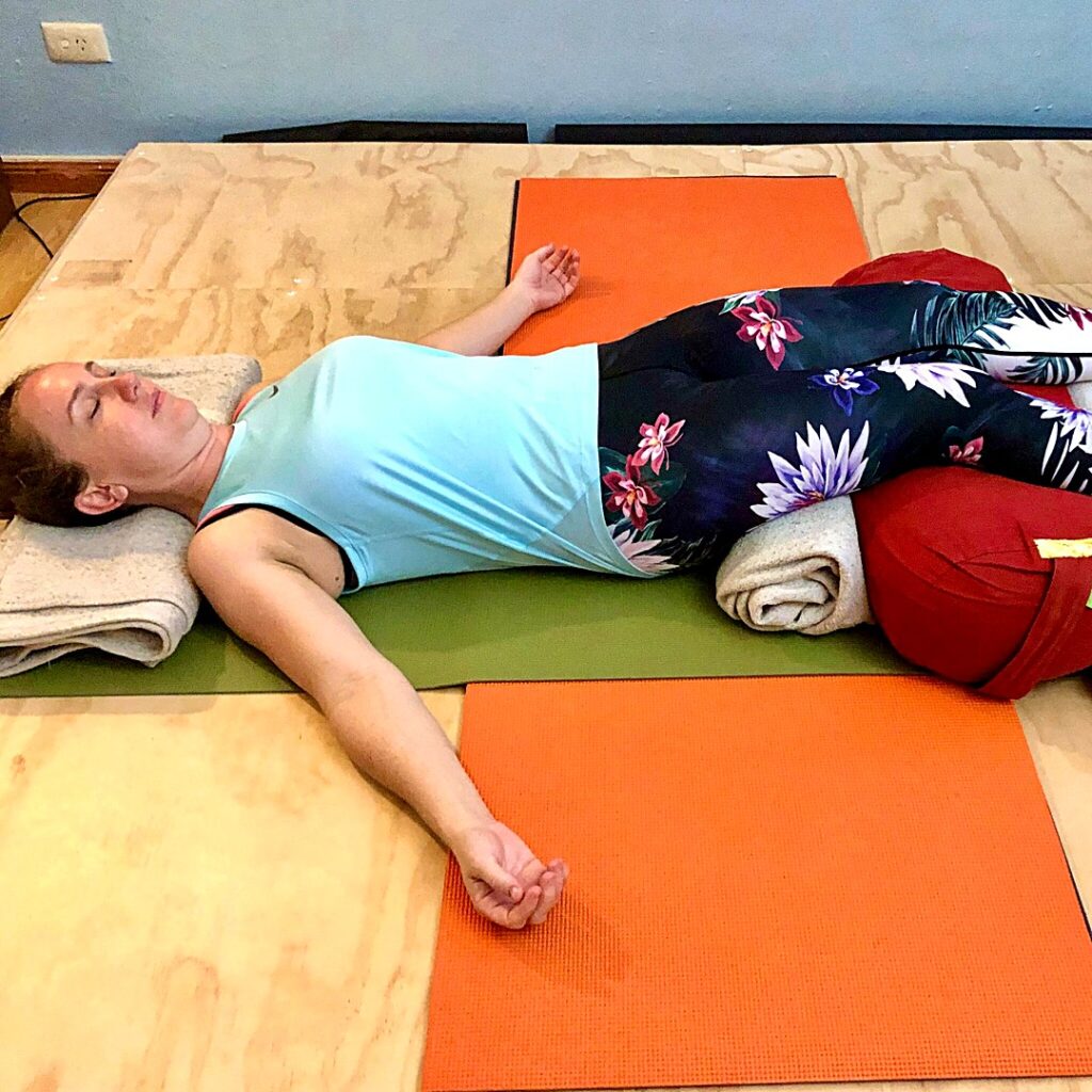 Slipped disc rest: Kim lying with her calves on a bolster and a blanket under her head, the back resting on the floor