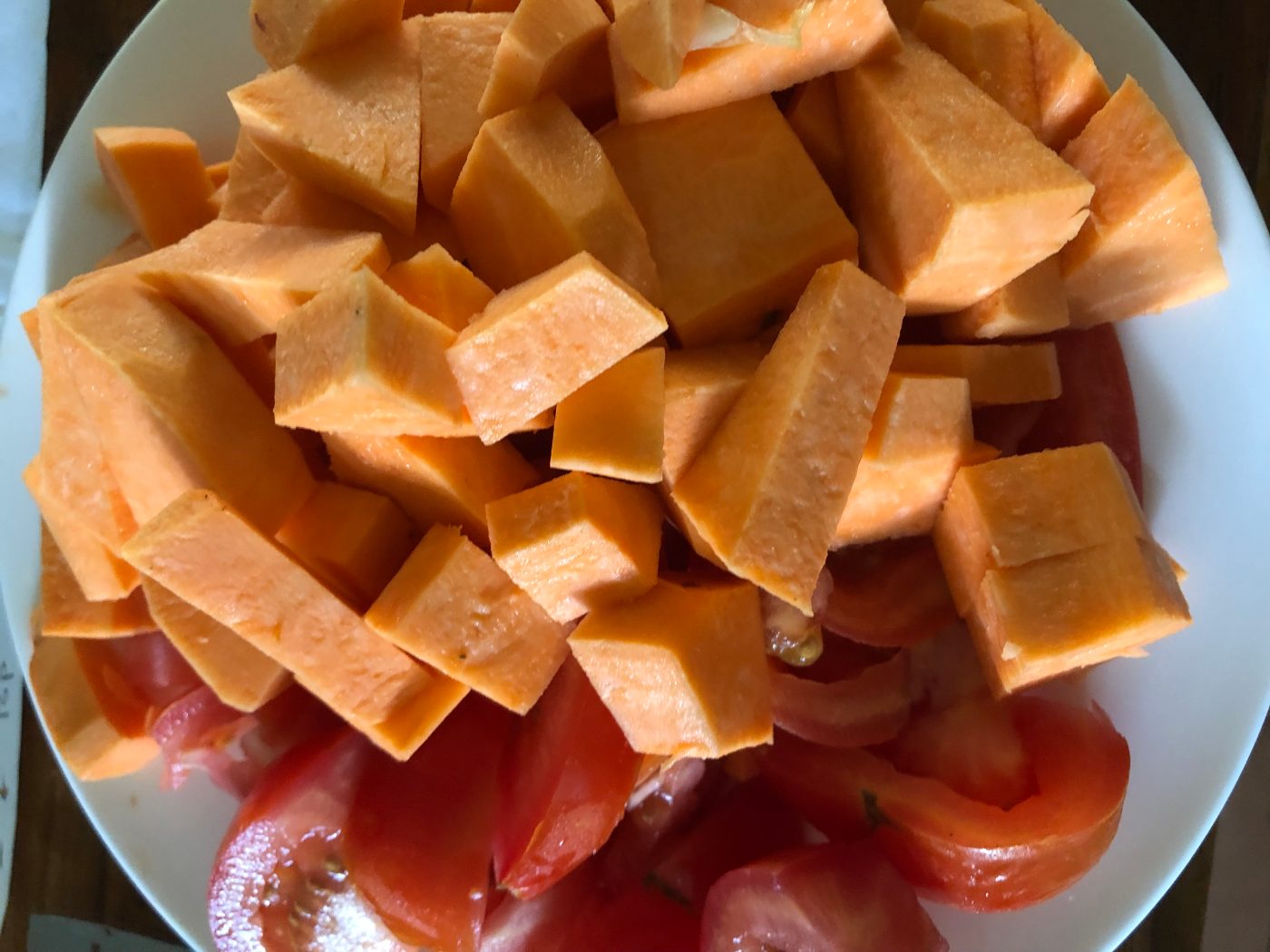 Sweet potato cut into small pieces with fresh tomatoes for a jackfruit curry