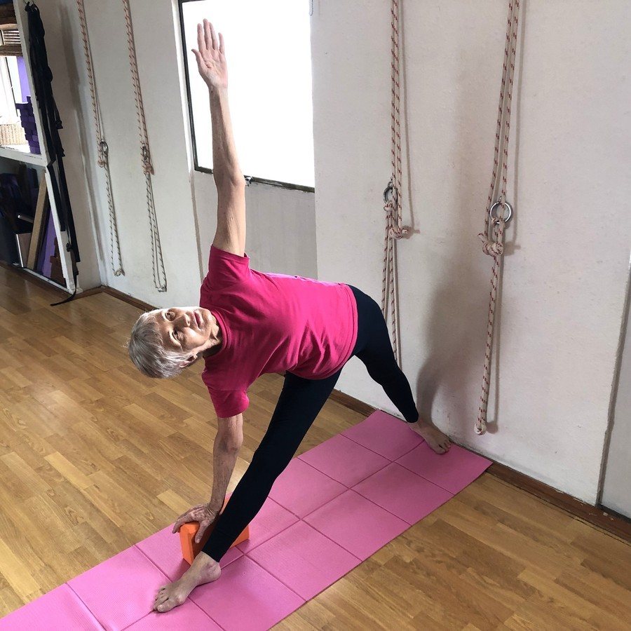 Kyphosis and a long spine: Chris Lalor in Triangle Pose at the rope wall, both legs straight, chest turning open and the upper arm reaching up