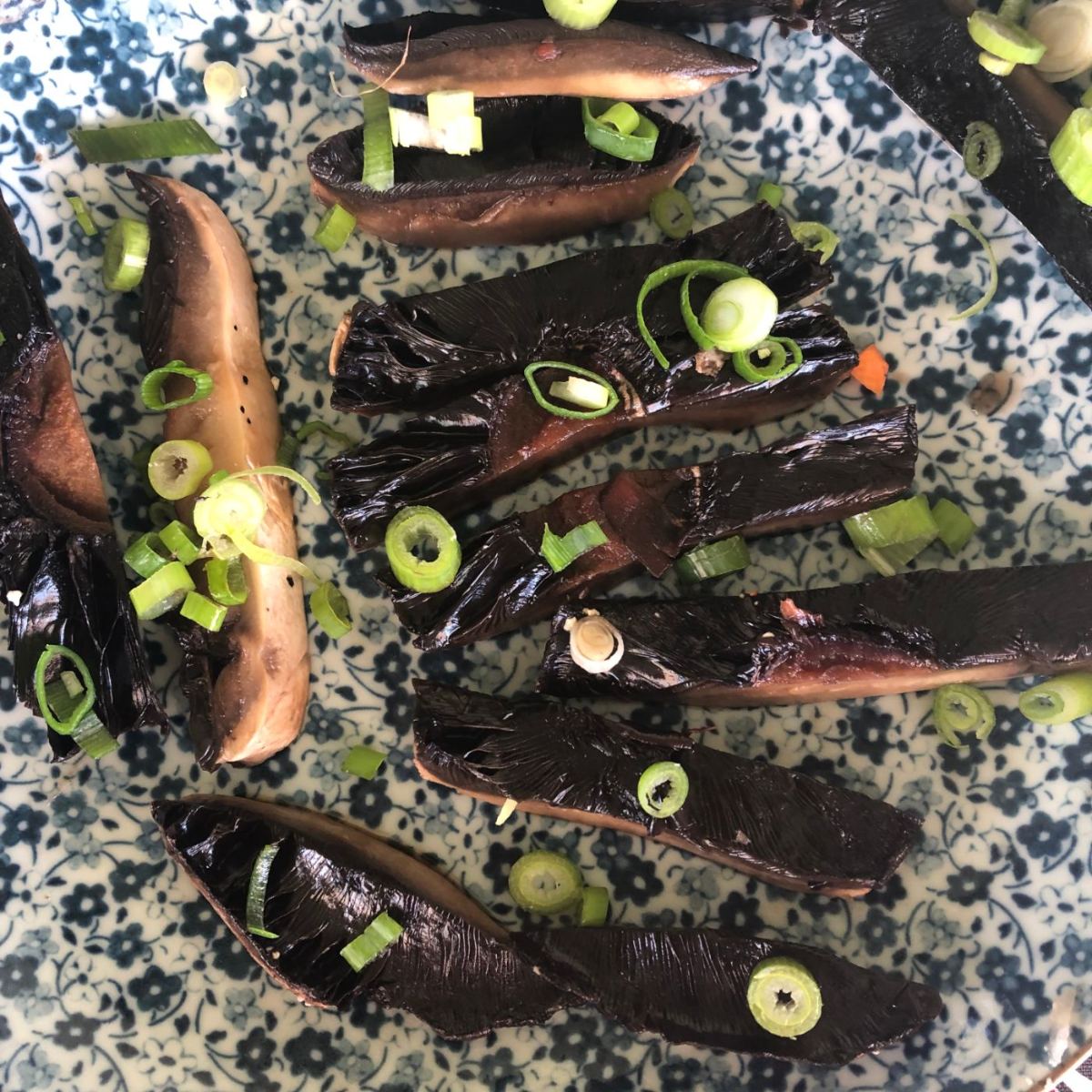 Close up of sliced tamari poached mushrooms with green spring onion rings