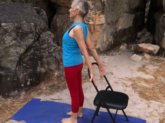 Over 60s exercise Darwin class: Chris Lalor standing tall in a sandstone gorge with one hand on the back of a chair for support