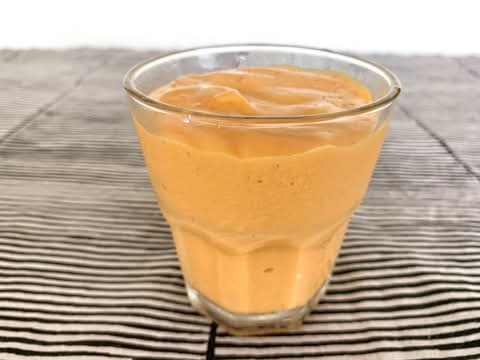 Glass of orange papaya smoothie on a striped cloth