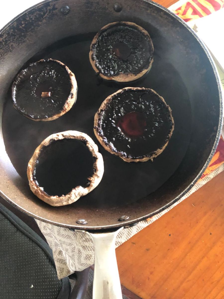 Four large peeled mushrooms poaching in a frypan of water with tamari and mirin for marinated mushrooms