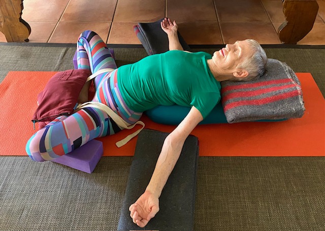 Yoga sandbag: Chris Lalor in Reclining Bound Angle Pose with a sandbag and belt on the legs