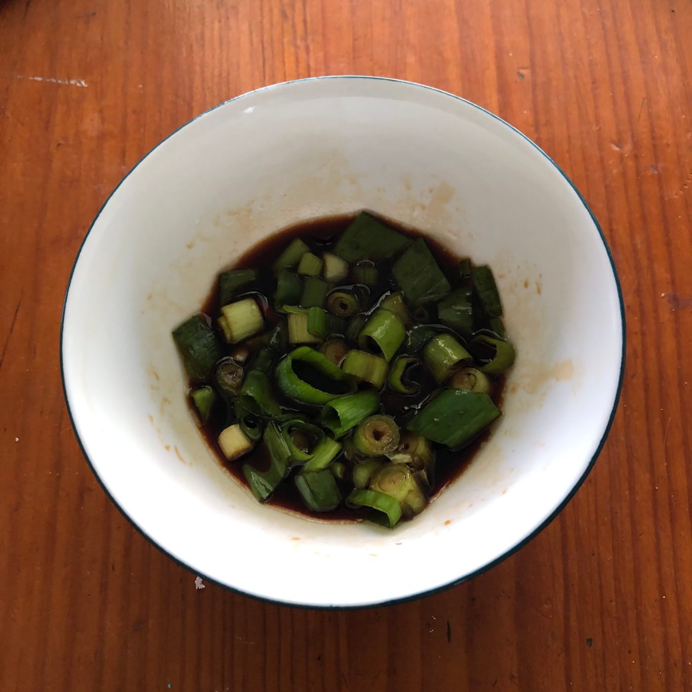 A small white bowl of chopped spring onions to serve with the gluten free wontons
