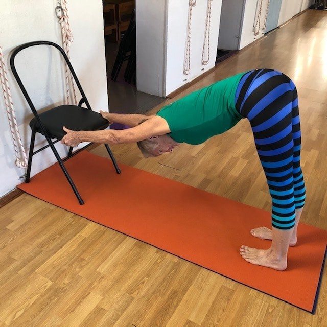 Upper back pain: a student working with a chair to lengthen the arms and open the upper back and shoulders
