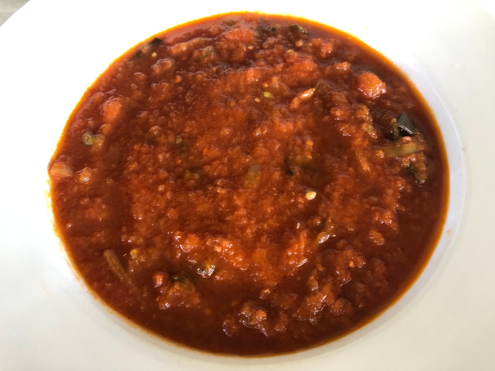 Close up of vegan tomato soup showing pieces of leek and green bean