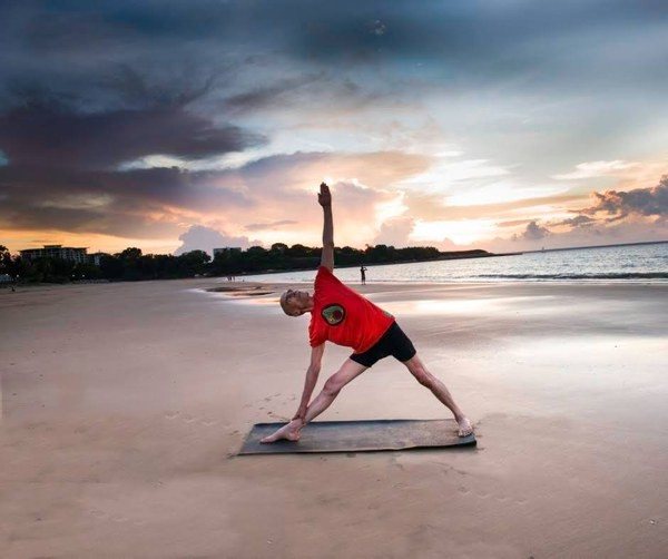 Yoga for golfers: Stuart in Triangle Pose on the beach at sunset, legs straight, one arm reaching to the sky