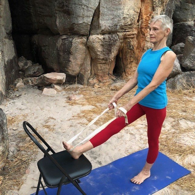Yoga for sore back: Chris Lalor in a standing leg stretch with one heel on a chair and a belt, Iyengar style